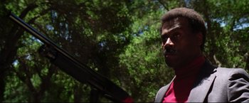 Movie still from “Sudden Impact” (1983), directed by Clint Eastwood – A man in a suit holding a gun in a forest; Close Up shot, Low angle