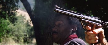 Movie still from “Sudden Impact” (1983), directed by Clint Eastwood – A man with a gun on his head in a forest; Close Up shot, Low angle