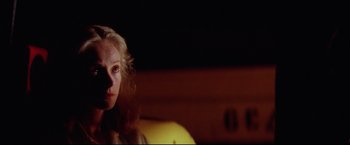 Movie still from “Sudden Impact” (1983), directed by Clint Eastwood – A woman sitting on a couch in a dark room; Close Up shot, Low angle