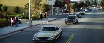 Movie still from “Sudden Impact” (1983), directed by Clint Eastwood – A car driving down a street next to a building; Extreme Wide shot, Low angle