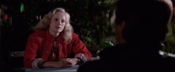 Movie still from “Sudden Impact” (1983), directed by Clint Eastwood – A woman sitting at a table with a man in the background; Medium shot, Over the shoulder angle