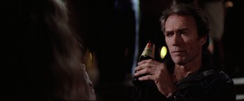 Movie still from “Sudden Impact” (1983), directed by Clint Eastwood – A man holding a bottle in his hand; Close Up shot, Over the shoulder angle