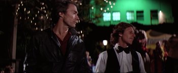 Movie still from “Sudden Impact” (1983), directed by Clint Eastwood – A man and a woman standing next to each other on a street; Medium shot, Over the shoulder angle
