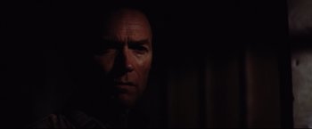 Movie still from “Sudden Impact” (1983), directed by Clint Eastwood – A person's face in the dark; Close Up shot, Over the shoulder angle