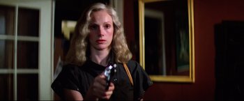 Movie still from “Sudden Impact” (1983), directed by Clint Eastwood – A woman holding a gun while standing next to a mirror; Close Up shot, Low angle
