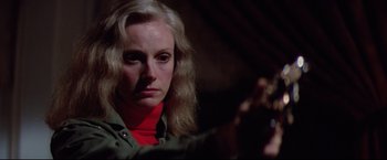 Movie still from “Sudden Impact” (1983), directed by Clint Eastwood – A woman holding a gun while wearing a red neck scarf; Close Up shot, Over the shoulder angle