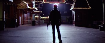 Movie still from “Sudden Impact” (1983), directed by Clint Eastwood – A man standing in the dark holding a gun; Wide shot, Low angle