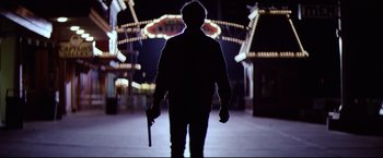 Movie still from “Sudden Impact” (1983), directed by Clint Eastwood – A person holding a gun in a dark place; Wide shot, Low angle