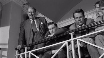 Movie still from “Suddenly, Last Summer” (1959), directed by Joseph L. Mankiewicz – A group of men sitting on a railing in a building; Medium shot, Low angle