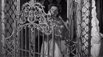 Movie still from “Suddenly, Last Summer” (1959), directed by Joseph L. Mankiewicz – An old photo of a woman standing in front of an iron gate; Medium shot, Low angle