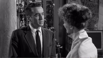 Movie still from “Suddenly, Last Summer” (1959), directed by Joseph L. Mankiewicz – An older man and a woman in a suit and tie talking to each other; Close Up shot, Over the shoulder angle
