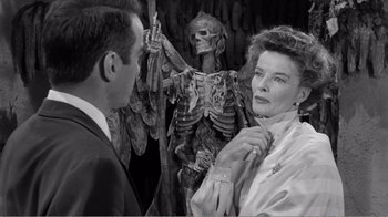 Movie still from “Suddenly, Last Summer” (1959), directed by Joseph L. Mankiewicz – A man and a woman standing in front of a skeleton; Medium shot, Over the shoulder angle