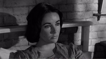 Movie still from “Suddenly, Last Summer” (1959), directed by Joseph L. Mankiewicz – Black and white photograph of a young woman in front of a brick wall; Close Up shot, High angle