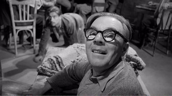 Movie still from “Suddenly, Last Summer” (1959), directed by Joseph L. Mankiewicz – An older man wearing glasses sitting on the ground; Medium shot, High angle