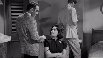 Movie still from “Suddenly, Last Summer” (1959), directed by Joseph L. Mankiewicz – A man and a woman are standing in front of another man; Medium shot, Over the shoulder angle
