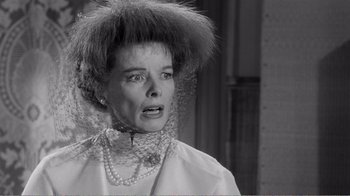 Movie still from “Suddenly, Last Summer” (1959), directed by Joseph L. Mankiewicz – An older woman wearing a white dress with a veil on top of her head; Close Up shot, Over the shoulder angle