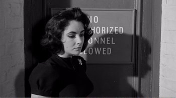 Movie still from “Suddenly, Last Summer” (1959), directed by Joseph L. Mankiewicz – A woman standing in front of a no authorized connell allowed sign; Close Up shot, Over the shoulder angle