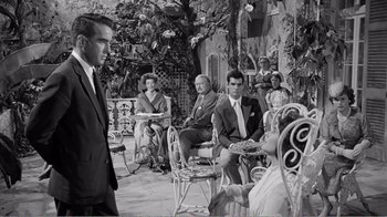 Movie still from “Suddenly, Last Summer” (1959), directed by Joseph L. Mankiewicz – A group of people sitting in chairs on a patio; Wide shot, Over the shoulder angle