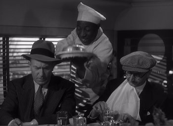 Movie still from “Sullivan's Travels” (1941), directed by Preston Sturges – A black and white photo of three men at a table; Medium shot, High angle