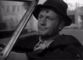 Movie still from “Sullivan's Travels” (1941), directed by Preston Sturges – A black and white photo of a man with a hat; Close Up shot, Over the shoulder angle