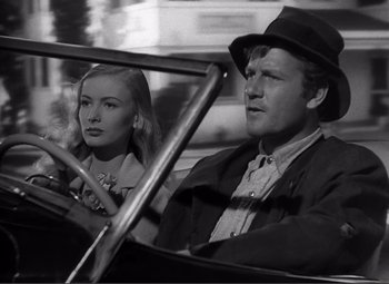 Movie still from “Sullivan's Travels” (1941), directed by Preston Sturges – A man and a woman driving a car in the street; Close Up shot, Low angle