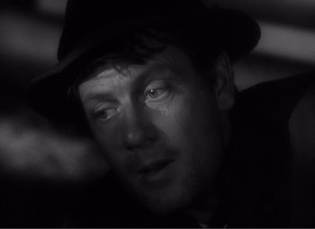 Movie still from “Sullivan's Travels” (1941), directed by Preston Sturges – A black and white photo of a man in a fedora; Close Up shot, Over the shoulder angle