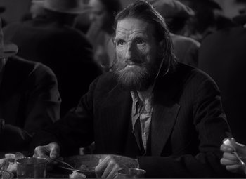 Movie still from “Sullivan's Travels” (1941), directed by Preston Sturges – An old man with a long beard sitting at a table; Close Up shot, Low angle