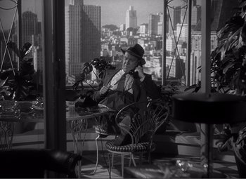 Movie still from “Sullivan's Travels” (1941), directed by Preston Sturges – A black and white photo of a man sitting in a chair; Wide shot, High angle