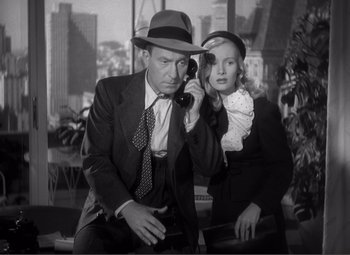 Movie still from “Sullivan's Travels” (1941), directed by Preston Sturges – A man and a woman sitting next to each other on a phone; Medium shot, Low angle