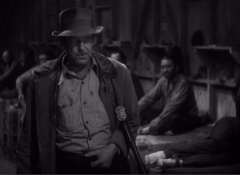 Movie still from “Sullivan's Travels” (1941), directed by Preston Sturges – A man with a hat and a gun in his hand; Medium shot, Over the shoulder angle