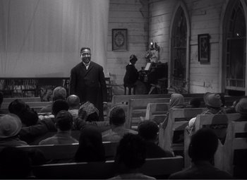 Movie still from “Sullivan's Travels” (1941), directed by Preston Sturges – A black and white photo of a man standing in front of a group of people; Wide shot, Low angle