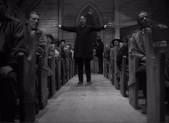 Movie still from “Sullivan's Travels” (1941), directed by Preston Sturges – Black and white photograph of a man standing in front of a crowd of people; Wide shot, Low angle
