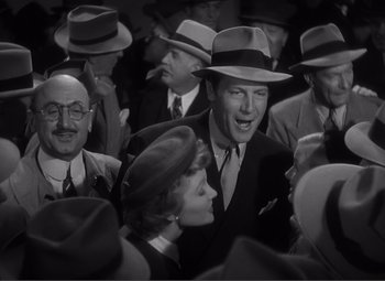 Movie still from “Sullivan's Travels” (1941), directed by Preston Sturges – A man and a woman in a crowd of people wearing hats; Medium shot, High angle