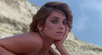 Movie still from “Summer Lovers” (1982), directed by Randal Kleiser – A beautiful woman sitting on top of a cliff; Close Up shot, High angle