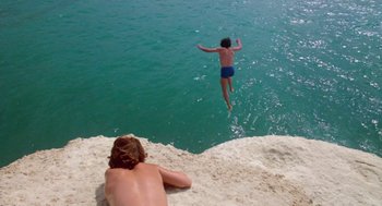 Movie still from “Summer Lovers” (1982), directed by Randal Kleiser – A man jumping off a cliff into the ocean; Wide shot, High angle