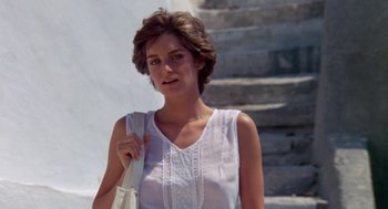 Movie still from “Summer Lovers” (1982), directed by Randal Kleiser – A woman in a white shirt holding a purse; Close Up shot, Low angle