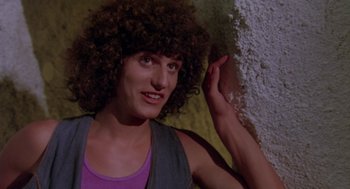 Movie still from “Summer Lovers” (1982), directed by Randal Kleiser – A man with a curly hair is posing for a picture; Close Up shot, Low angle