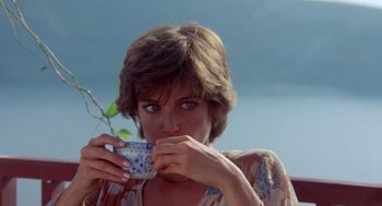 Movie still from “Summer Lovers” (1982), directed by Randal Kleiser – A person drinking a cup of coffee; Close Up shot, Low angle