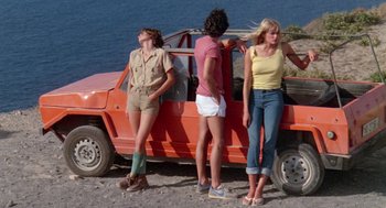 Movie still from “Summer Lovers” (1982), directed by Randal Kleiser – A group of people standing next to a red car; Wide shot, Low angle