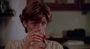 Movie still from “Summer Lovers” (1982), directed by Randal Kleiser – A woman holding a wine glass in front of her face; Close Up shot, Over the shoulder angle
