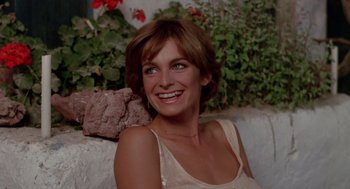 Movie still from “Summer Lovers” (1982), directed by Randal Kleiser – A woman sitting in front of a flower bush; Close Up shot, High angle
