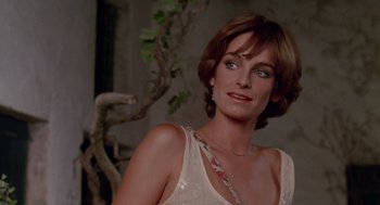 Movie still from “Summer Lovers” (1982), directed by Randal Kleiser – A person with short hair wearing a dress; Close Up shot, Over the shoulder angle