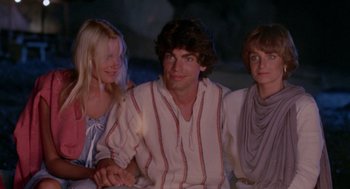 Movie still from “Summer Lovers” (1982), directed by Randal Kleiser – A man and two women sitting next to each other; Medium shot, Low angle