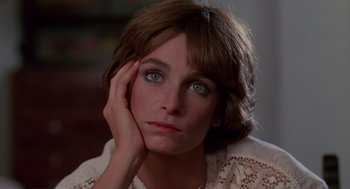 Movie still from “Summer Lovers” (1982), directed by Randal Kleiser – A person sitting with her hand on her face; Close Up shot, High angle