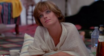 Movie still from “Summer Lovers” (1982), directed by Randal Kleiser – A woman in a white shirt is laying on a bed; Close Up shot, High angle