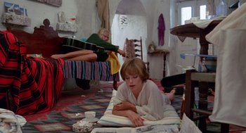 Movie still from “Summer Lovers” (1982), directed by Randal Kleiser – A woman laying on the ground in a room; Wide shot, High angle