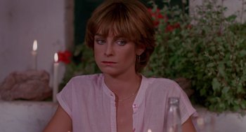 Movie still from “Summer Lovers” (1982), directed by Randal Kleiser – A person sitting at a table; Close Up shot, Over the shoulder angle