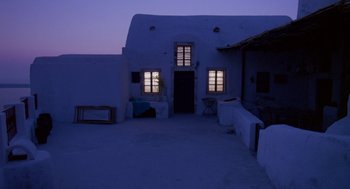 Movie still from “Summer Lovers” (1982), directed by Randal Kleiser – A building with a door and windows lit up at night; Extreme Wide shot, High angle