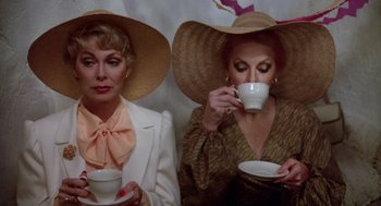 Movie still from “Summer Lovers” (1982), directed by Randal Kleiser – A couple of women sitting next to each other holding coffee cups; Close Up shot, High angle