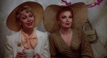 Movie still from “Summer Lovers” (1982), directed by Randal Kleiser – A couple of women sitting next to each other wearing hats; Close Up shot, Low angle